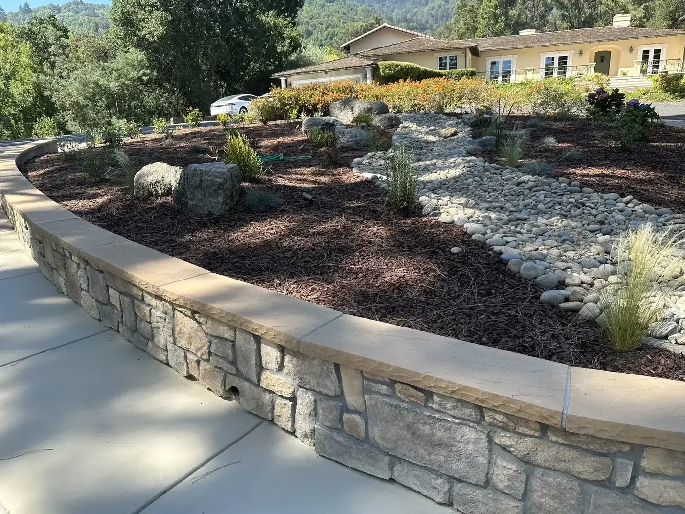 Curved block retaining wall with a dry creek bed